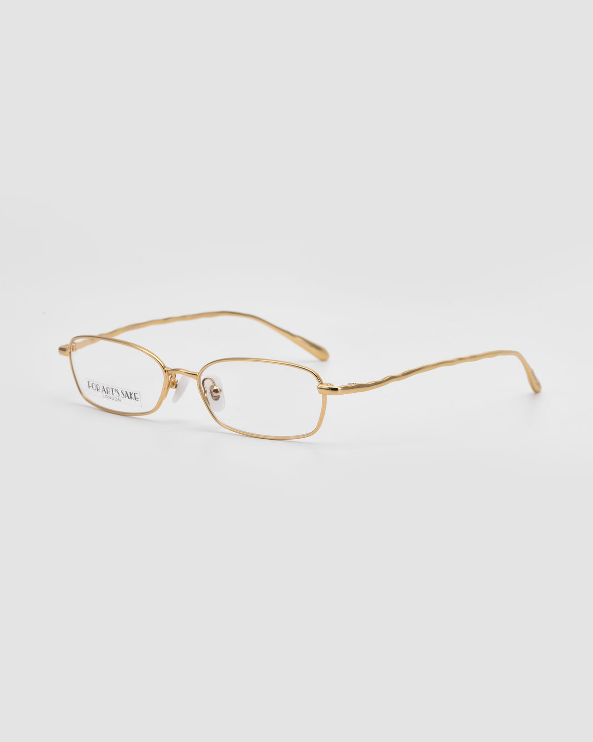 Suree I by For Art’s Sake®: Gold wireframe metal glasses with oval lenses, shown on a white background at an angle to highlight the front and one curved temple arm.