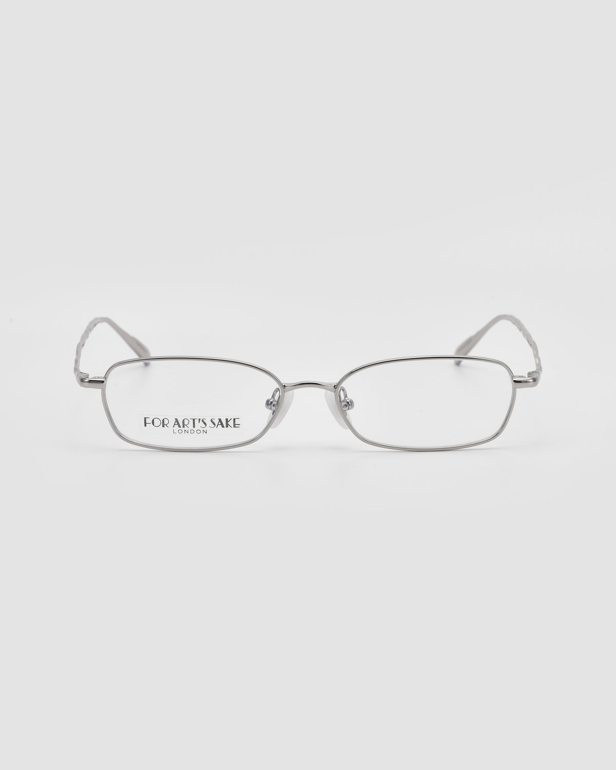 Silver-framed metal Suree I glasses by For Art’s Sake®, featuring a rectangular silhouette and clear lenses, shown front-facing on a white background. “FOR ART’S SAKE LONDON” appears on the left lens.