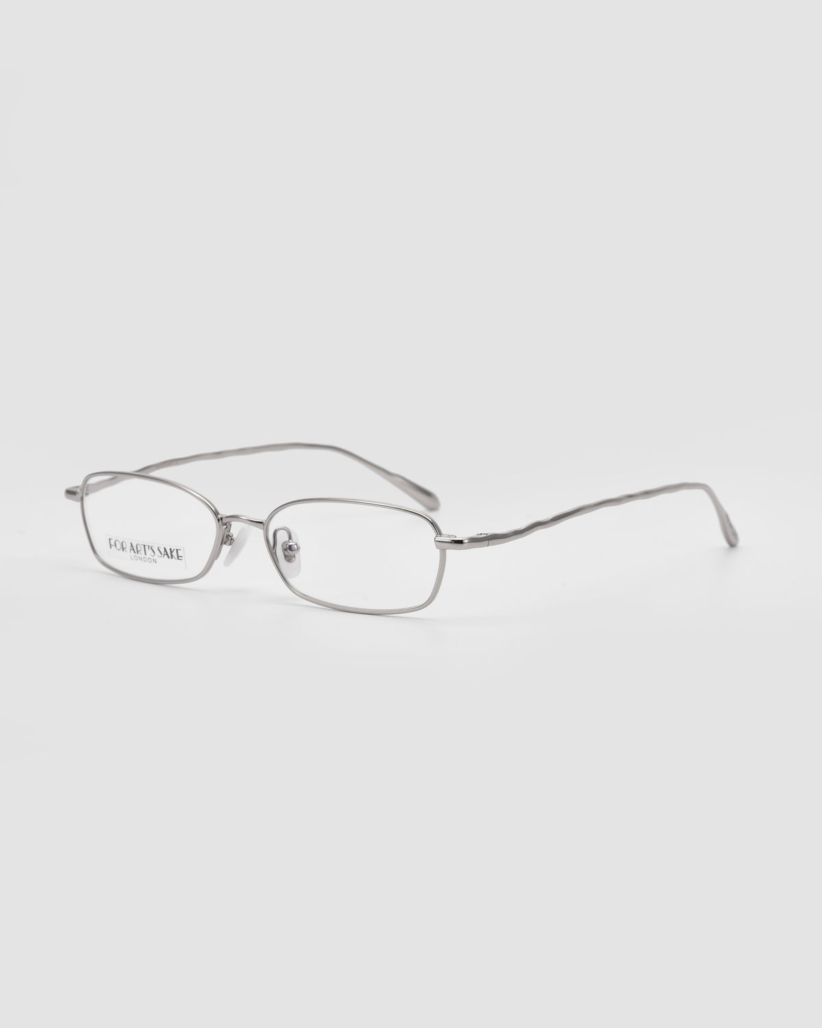For Art’s Sake® Suree I silver wireframe metal glasses with a rectangular silhouette are displayed on a plain light gray background, angled to show both the front and side views.