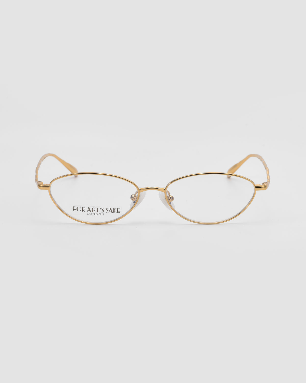 Suree II by For Art’s Sake®: Gold-rimmed, cat-eye optical frames with clear lenses are shown against a plain white background. The left lens is printed with “FOR ART’S SAKE LONDON.”.