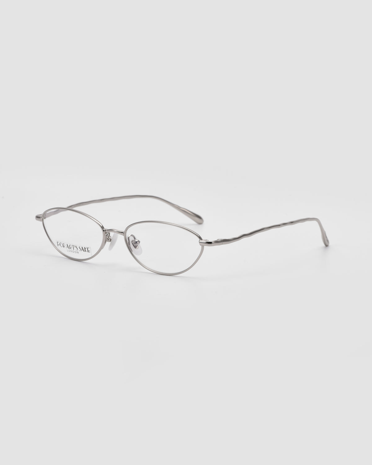 For Art’s Sake® Suree II: Silver, oval silhouette eyeglasses with thin metal frames, clear lenses, and flexible nose pads for comfort. Displayed on a white background.