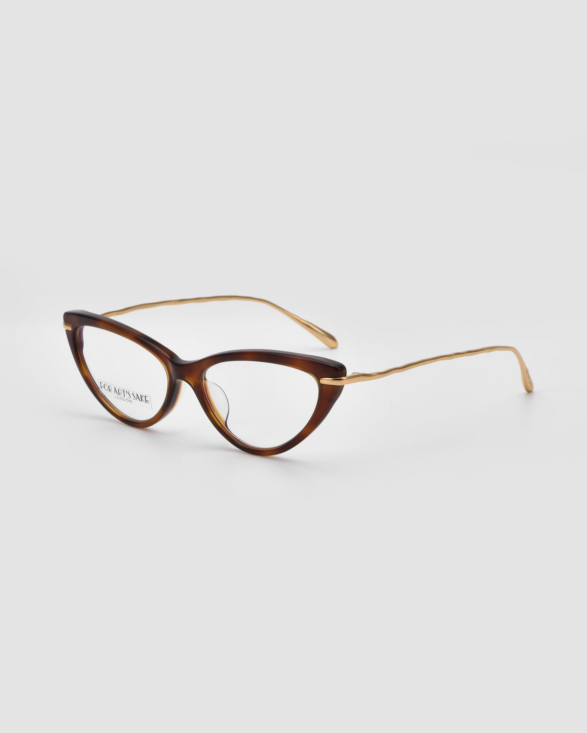 Solange by For Art’s Sake®: brown and gold cat-eye opticals with sculpted metal temples and thin, wavy gold arms, shown on a plain light gray background.