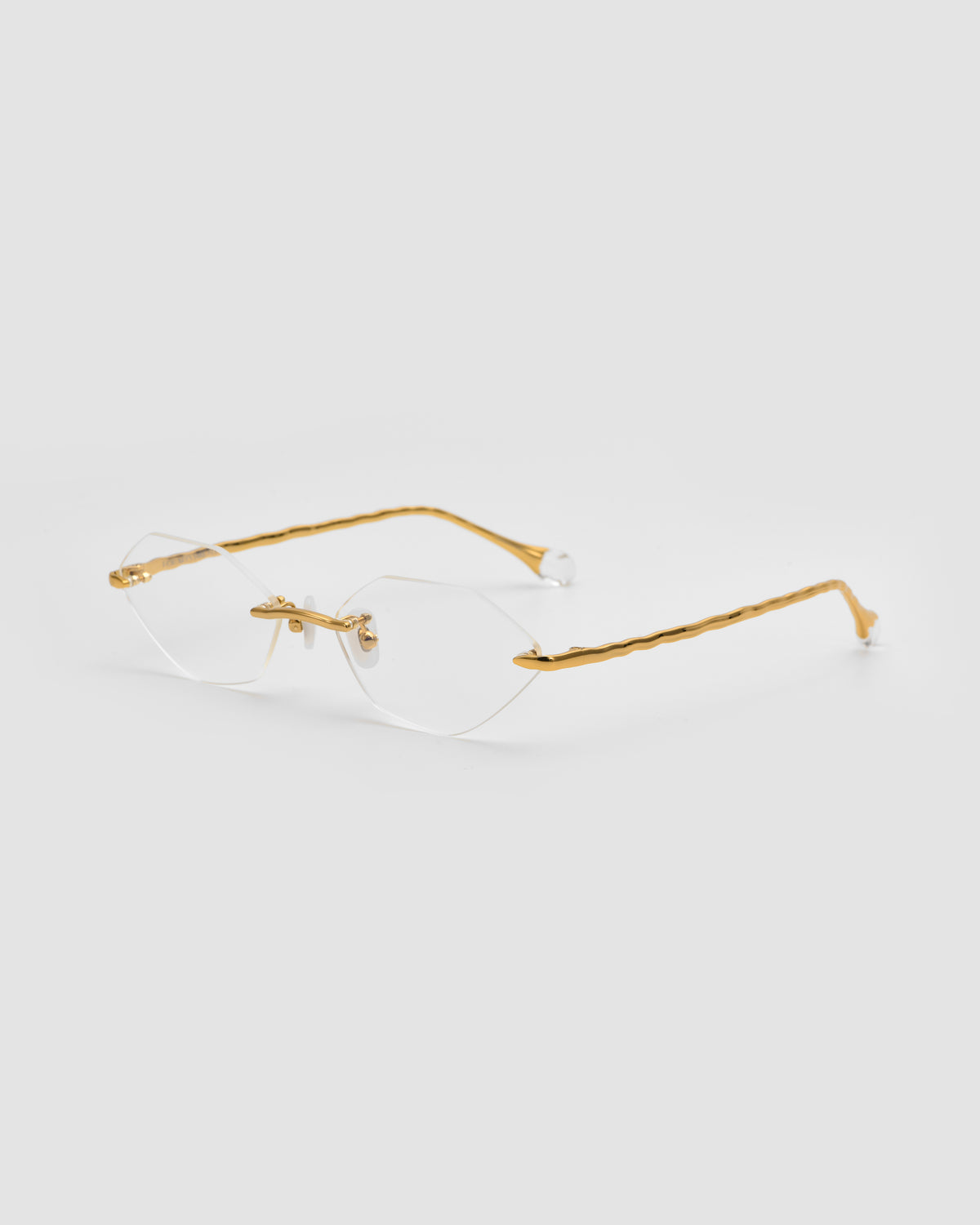 Amara I by For Art’s Sake®: Rimless eyeglasses with thin gold metal temples, sculpted nylon tips, and clear lenses. Minimalist, modern design from the Sol State collection shown on a white background.