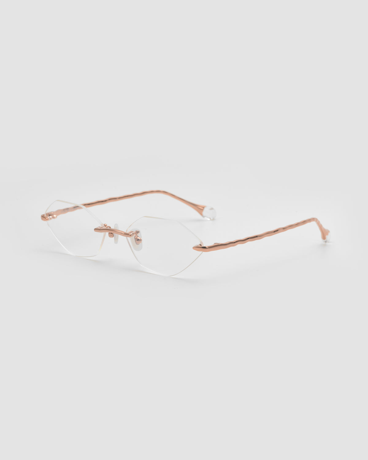 Amara I by For Art’s Sake®: rimless eyeglasses with thin rose gold temples, sculpted nylon tips, and clear nose pads, shown on a light gray background.