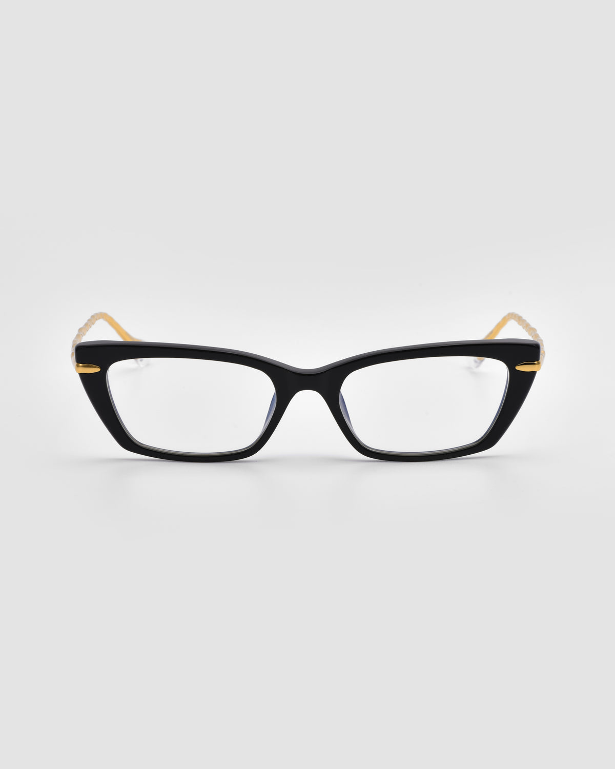 The Amara II by For Art’s Sake® is a black cat-eye optical frame with thick rims, gold temple accents, sculpted nylon tips, and a Translucent Jewel detail, shown on a plain white background.