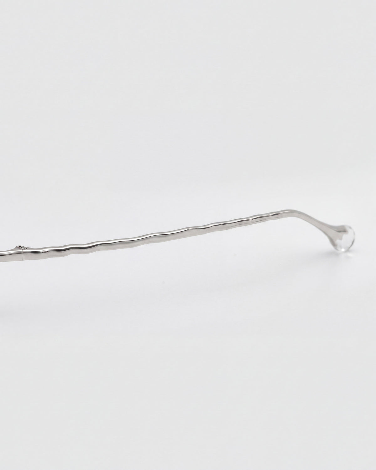 The Amara II by For Art’s Sake®—a single silver metal hairpin with a wavy design and rounded nylon temple tip—rests horizontally on a plain white background.