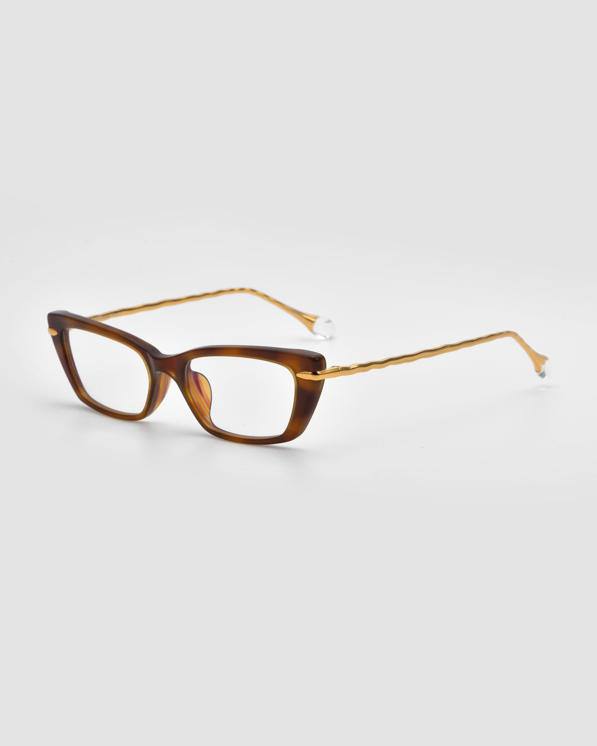 Amara II by For Art’s Sake®: a brown rectangular optical frame with thick rims, thin twisted arms, and sculpted nylon temple tips shown on a light grey background.
