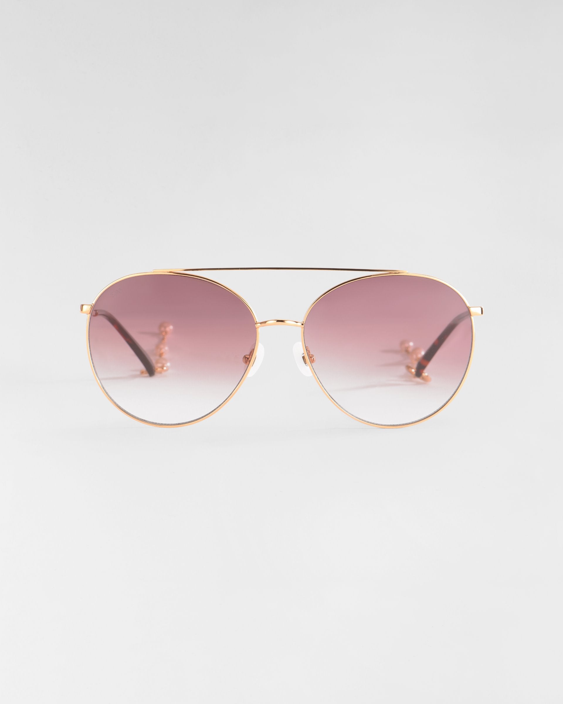 The Yoyo - ARC sunglasses by For Art's Sake® feature handmade 18-karat gold plating, gradient pink lenses on a white backdrop, and an elegant design with a double bridge, thin black temples, and clear nose pads.