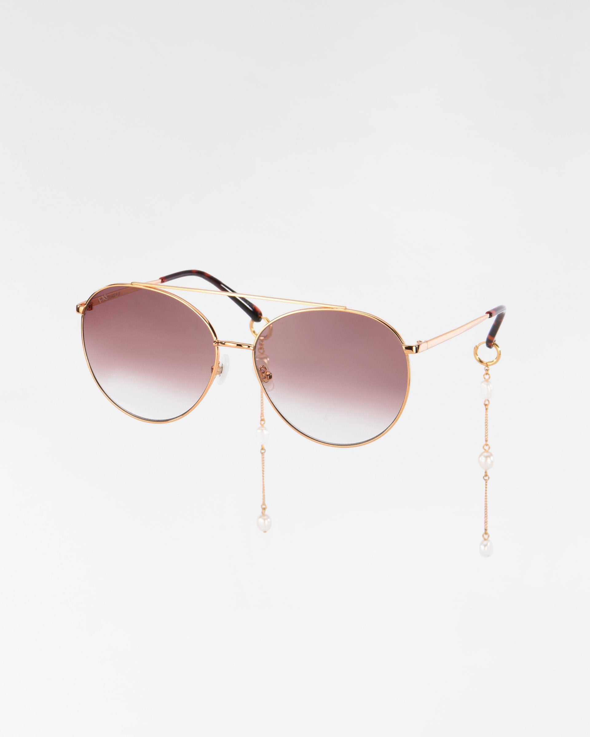Yoyo - ARC by For Art's Sake® are round, handmade sunglasses with 18-karat gold-plated frames and gradient brown lenses, featuring decorative pearl chains attached to the temples, set against a plain white background.
